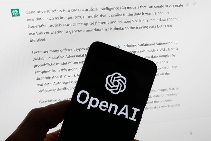 El logotipo de OpenAI se ve en un teléfono móvil frente a una pantalla de computadora que muestra el resultado de ChatGPT. - Ilustración: Michael Dwyer (AP)