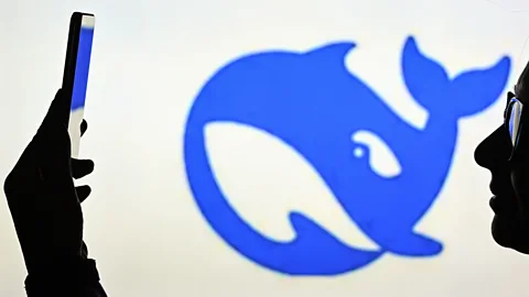 Getty Images Una mujer parece un teléfono con el logotipo de Deepseek en segundo plano (crédito: Getty Images)