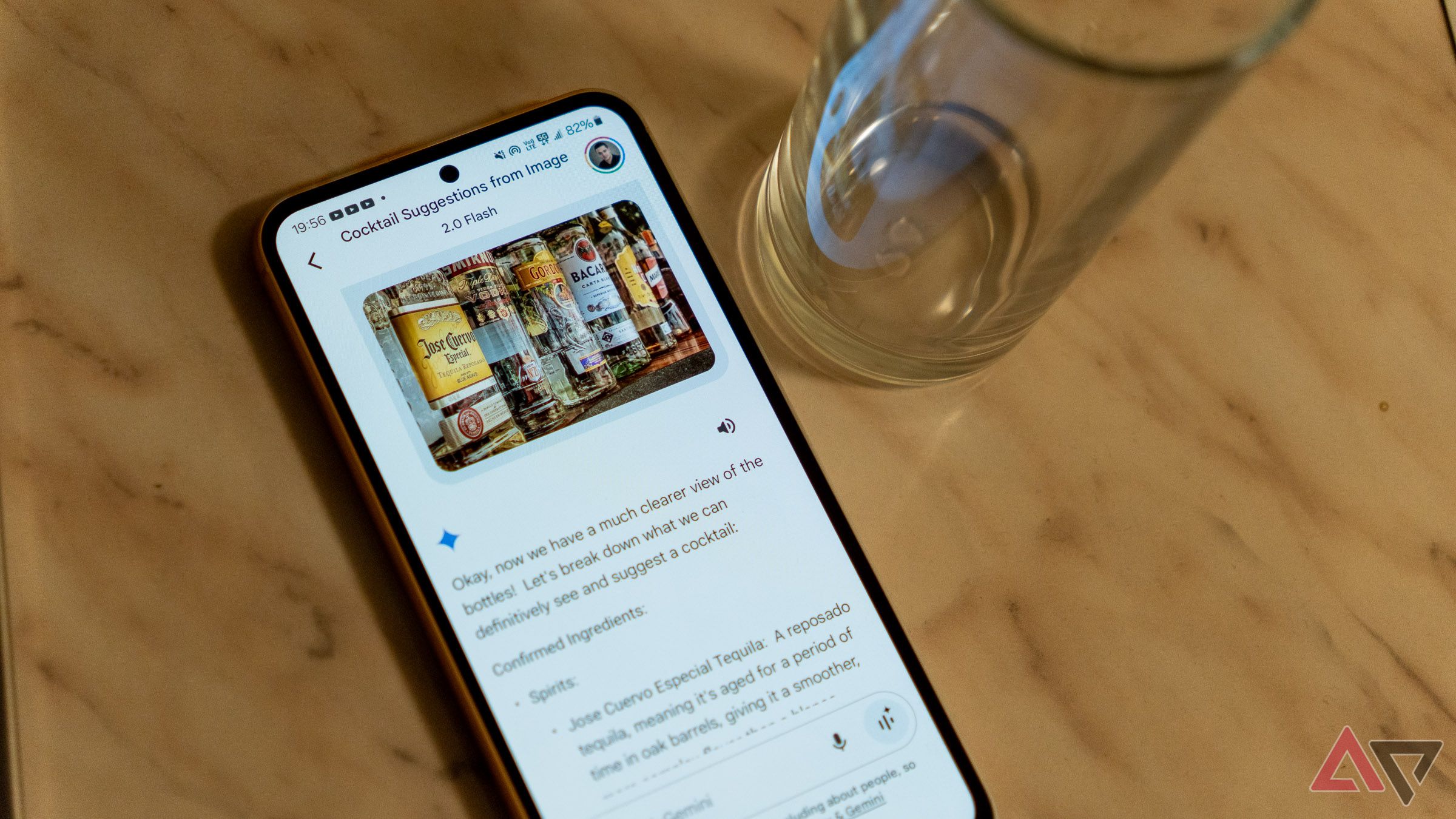 Se abre un teléfono Samsung Galaxy en una encimera al lado de un vaso con la aplicación Google Gemini