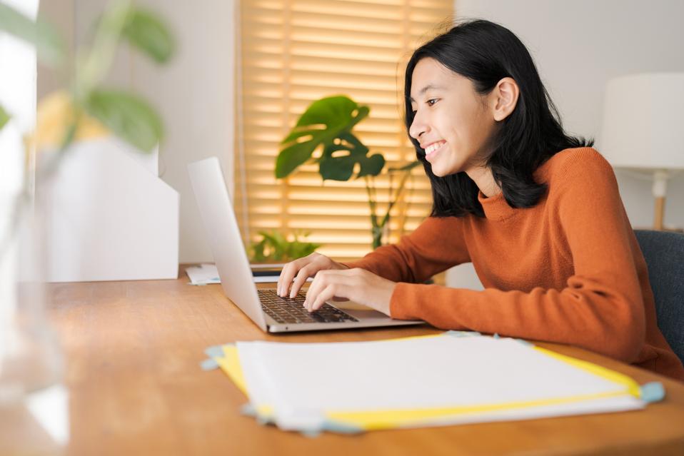 Chica asiática que usa computadora portátil en casa mañana